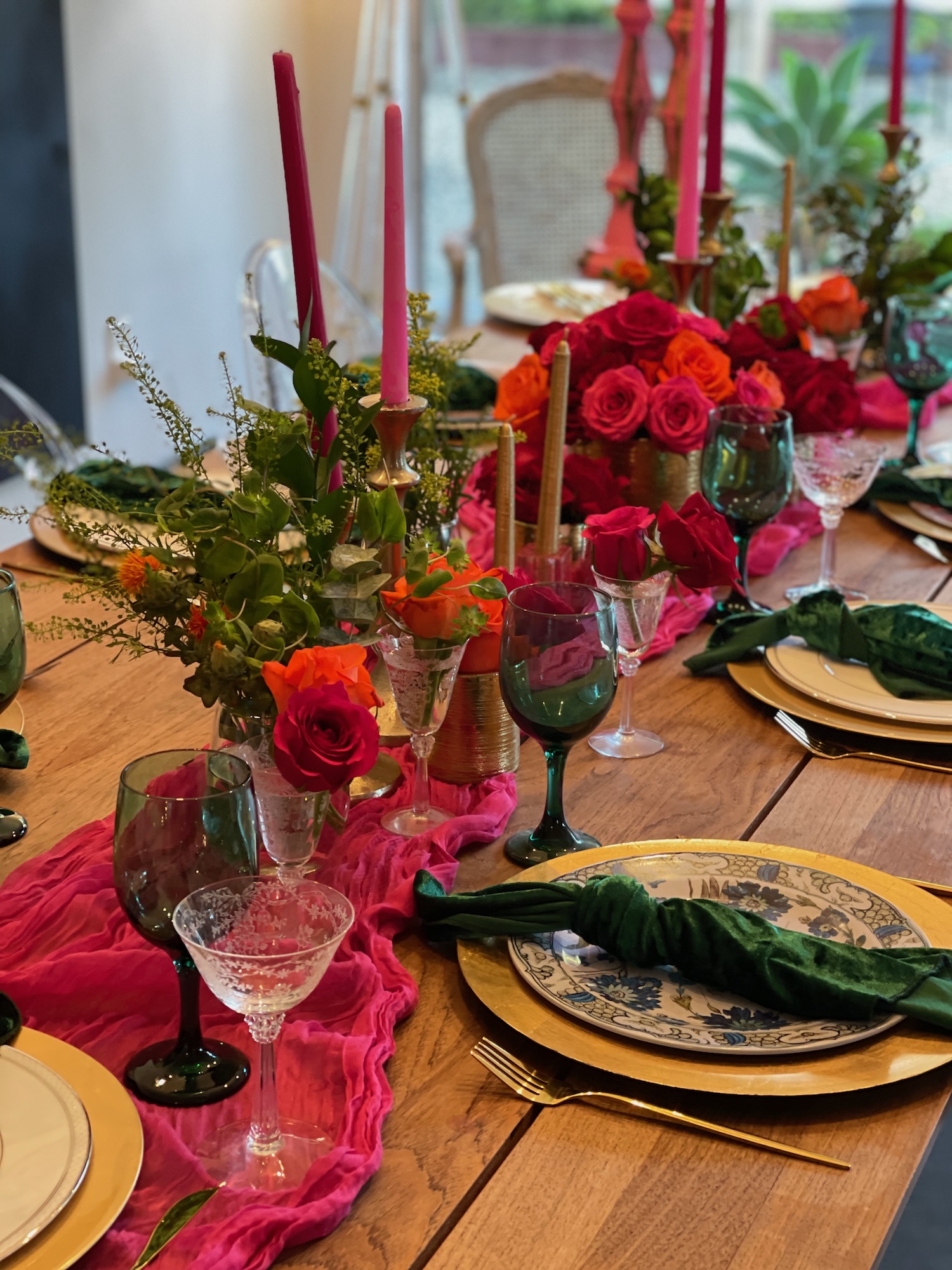 Vibrant fuchsia and emerald tablescape with roses and tapers
