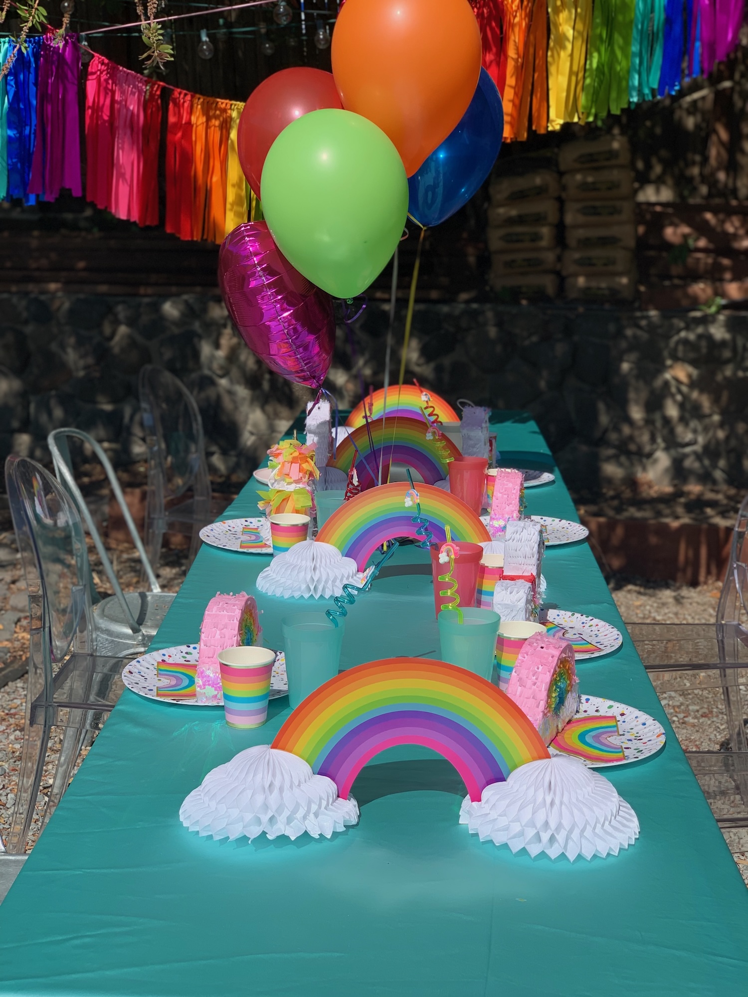 Rainbow children's party table with balloons and piñatas