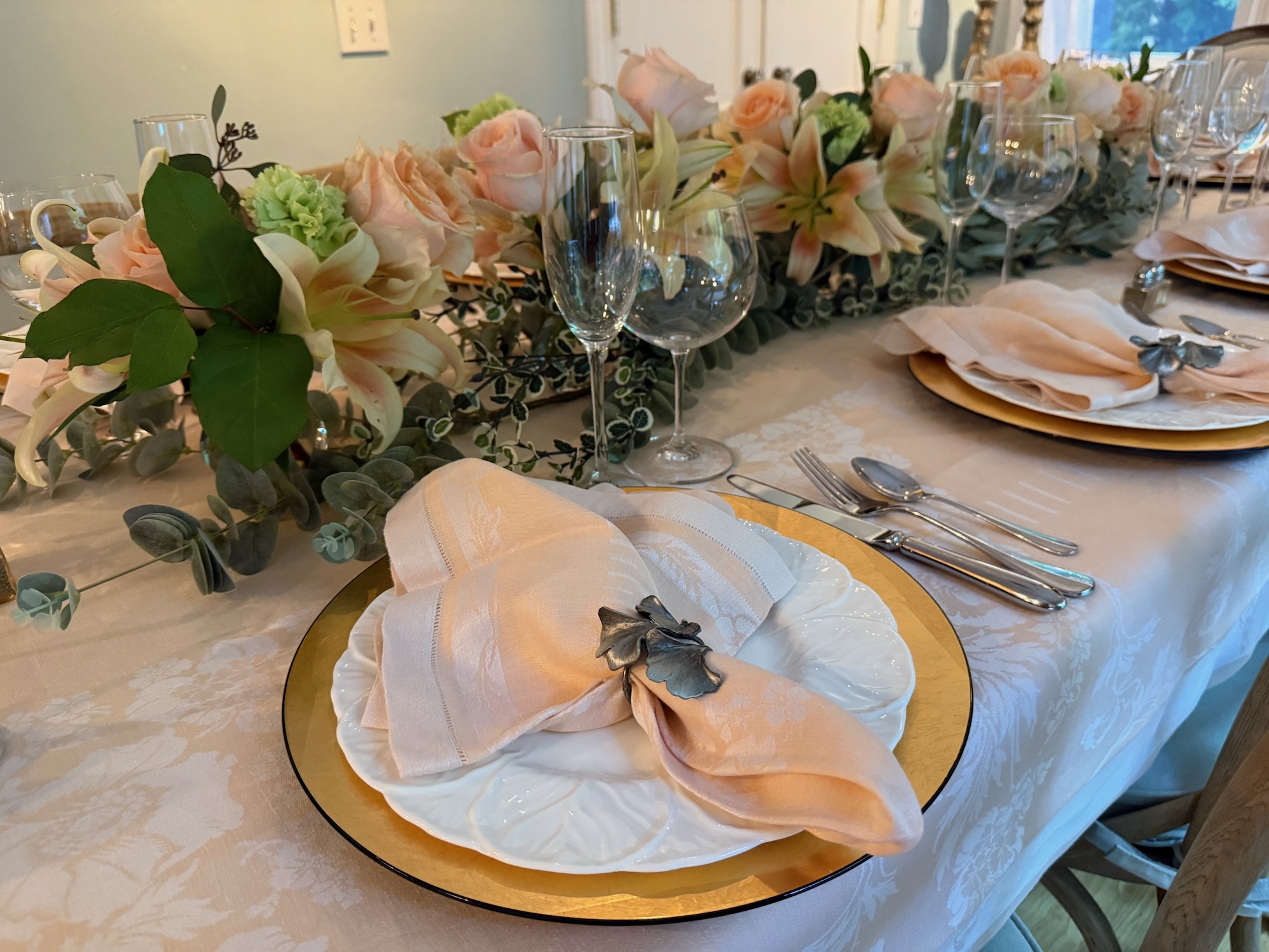 Place setting detail with gold charger and peach floral runner