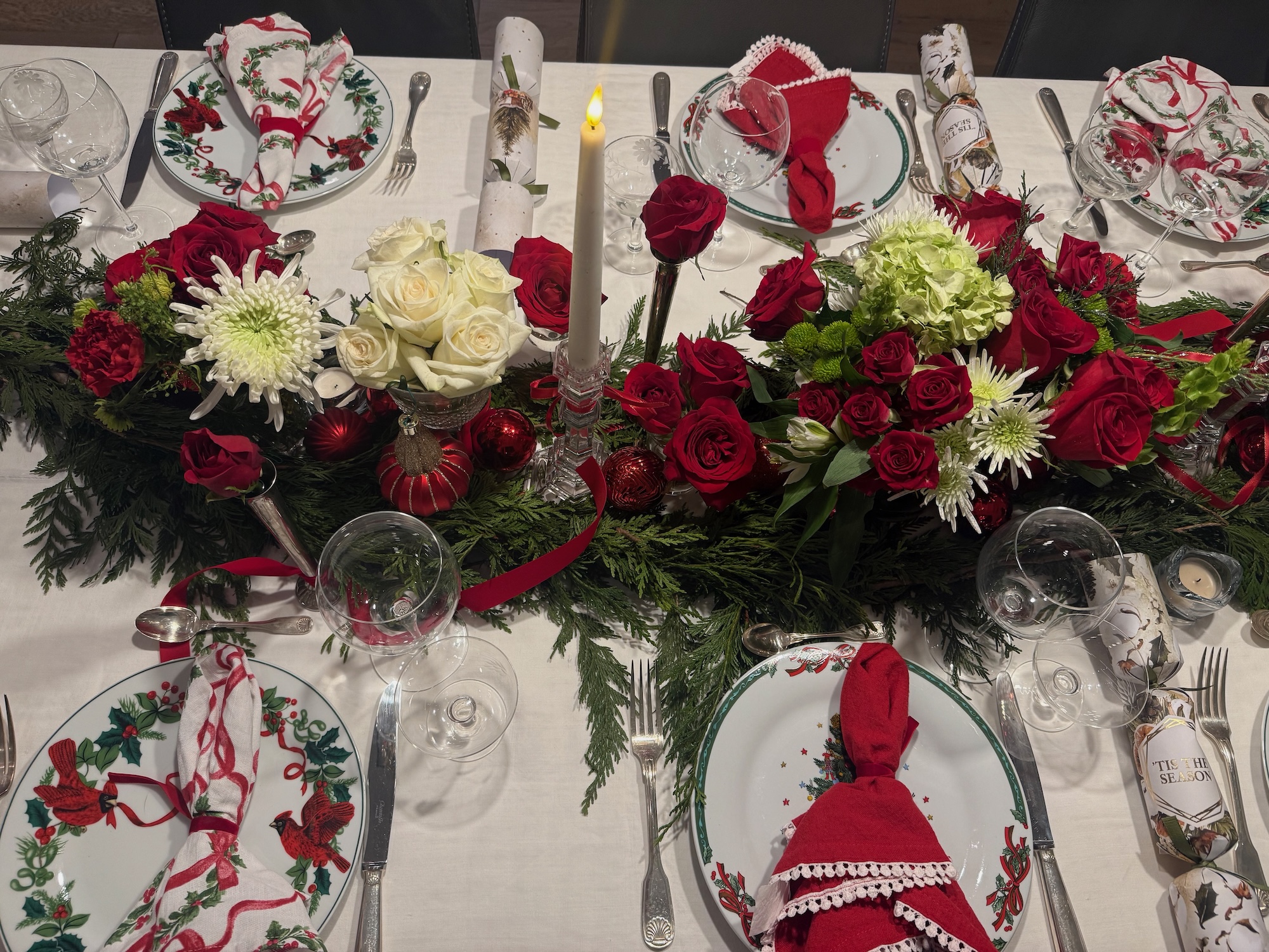 Holiday table setting with evergreens, roses and festive china