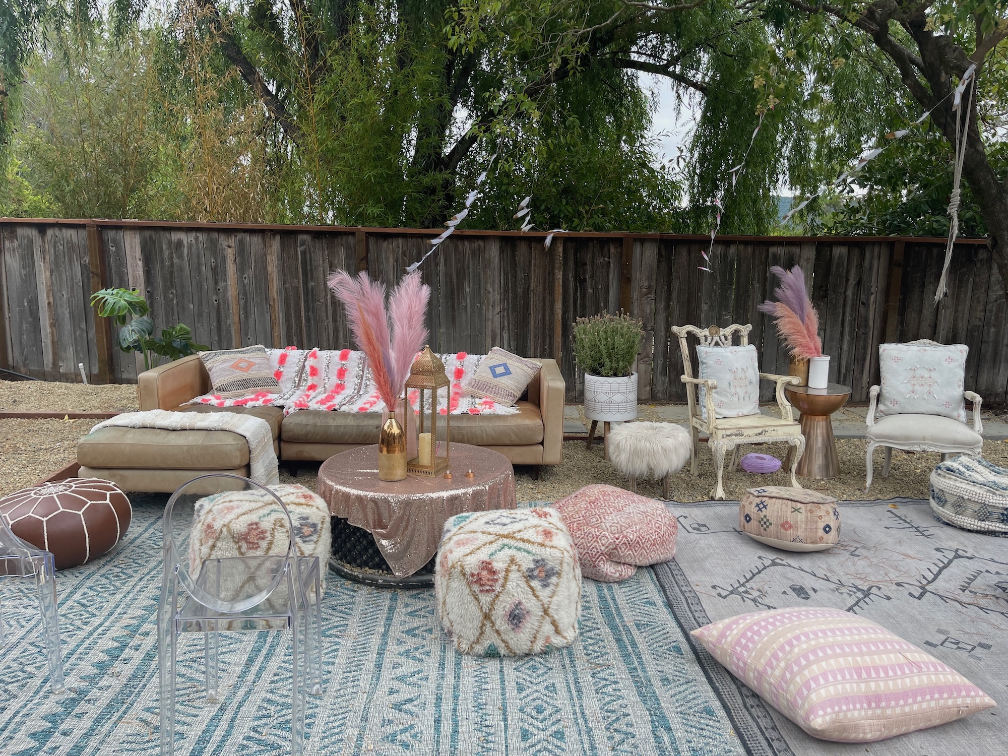Outdoor lounge setup with rugs, poufs and blush accents