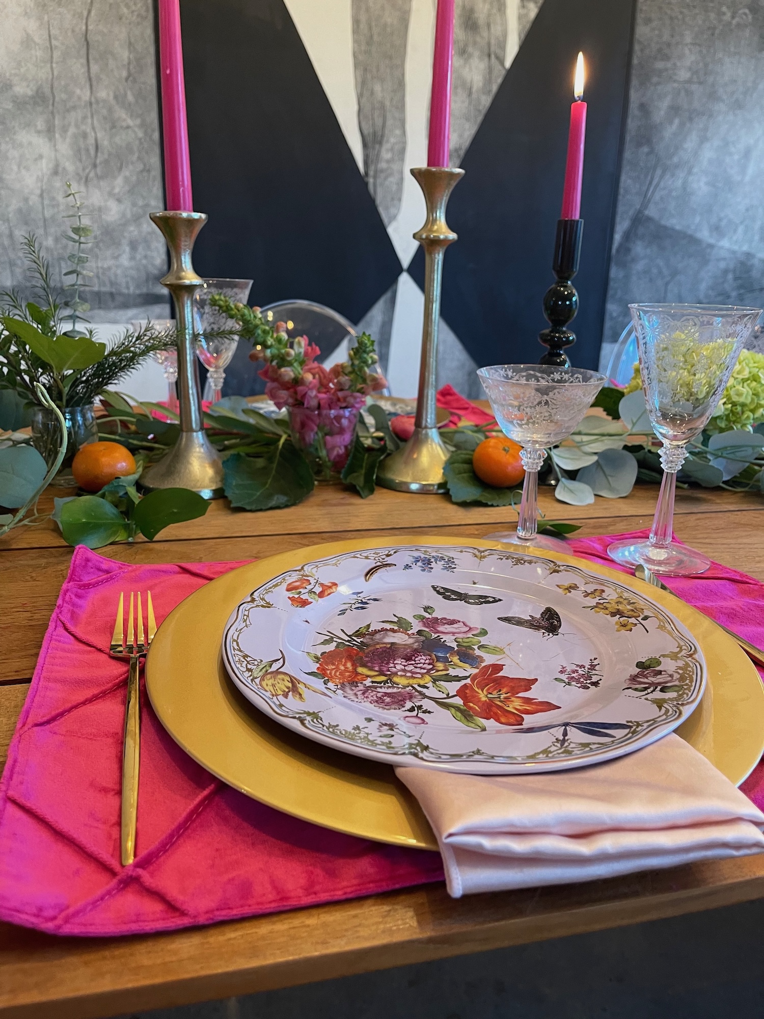Eclectic place setting with pink taper candles, floral plate and citrus accents